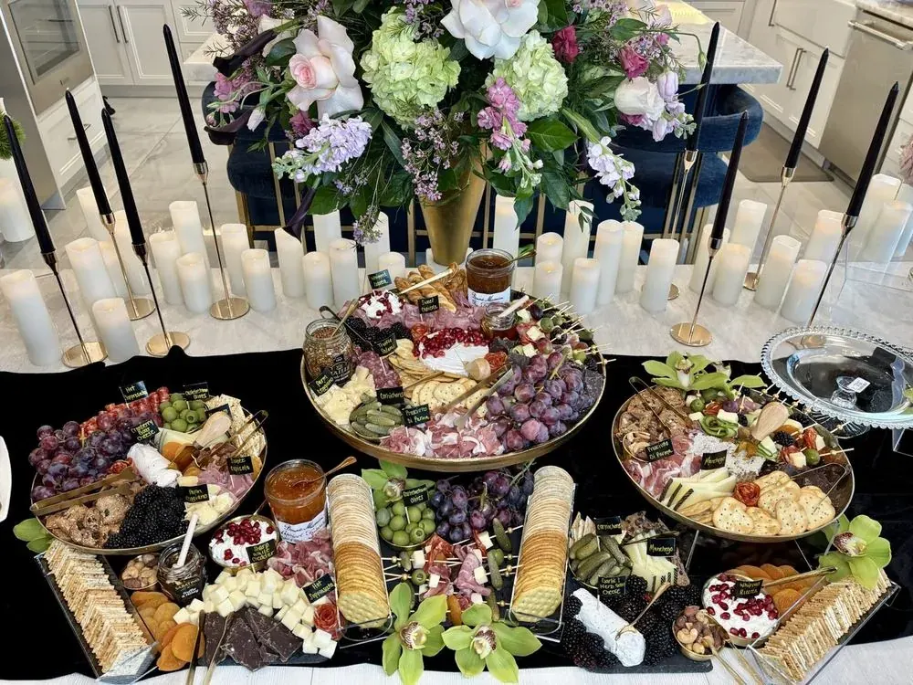 A styled charcuterie spread of meats, cheeses, fruit, and florals on tiered boards