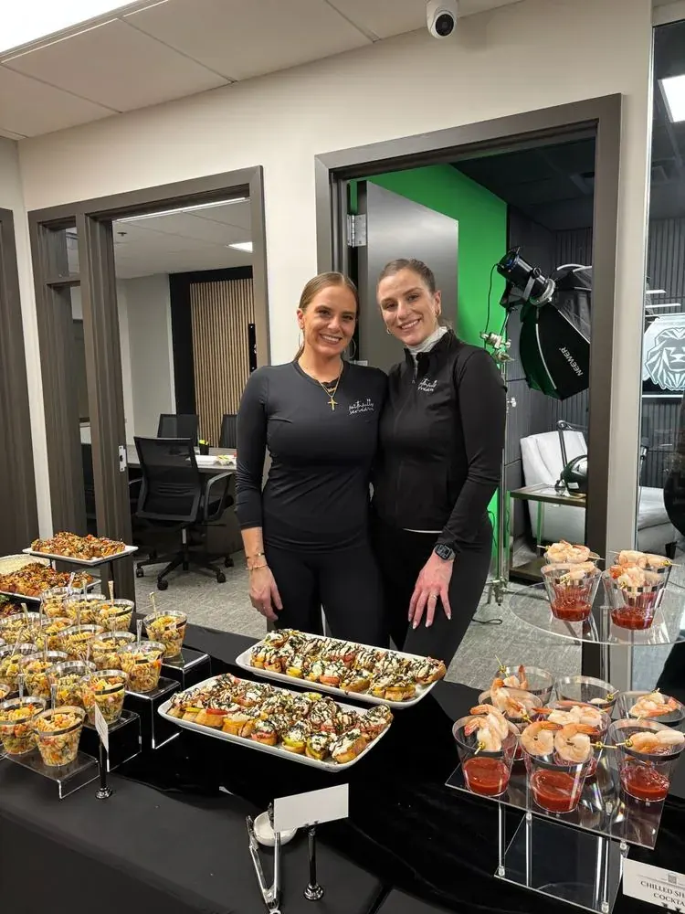Chef Selena and Mariah beside a styled corporate grazing spread