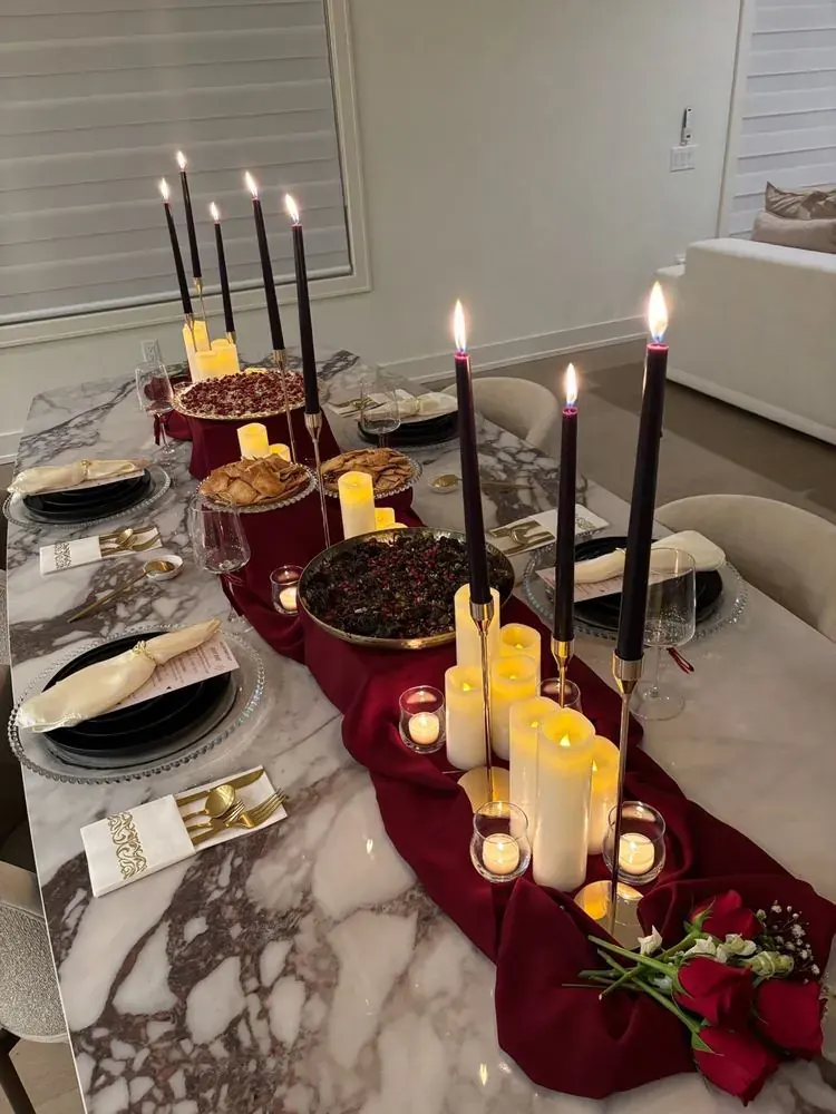 A candlelit tablescape with a red runner and grazing centerpiece