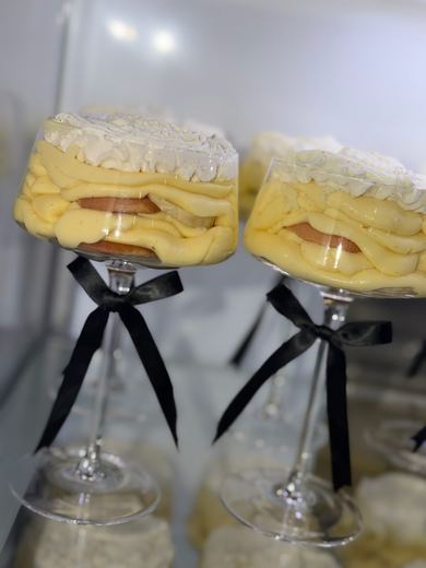 Individual layered dessert parfaits in stemmed glasses tied with black ribbon