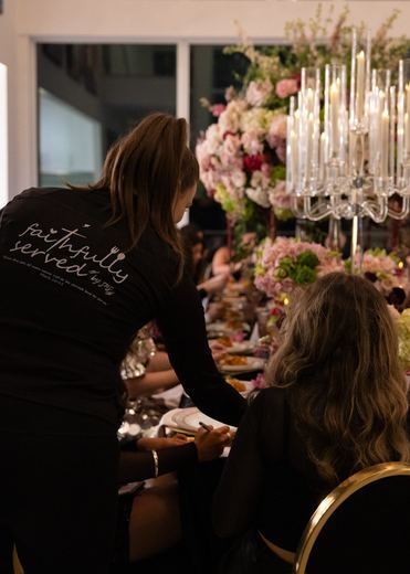 A Faithfully Served server placing a course at a candlelit dinner table