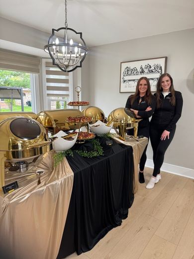 The team beside a gold chafing-dish buffet set up in a client's home